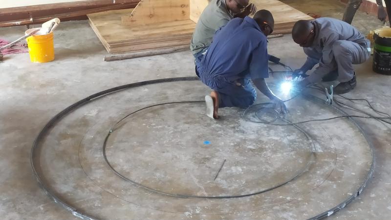 Educators master the pivotal processes of bending and welding to construct the parabolic skeleton of industrial solar cookers.